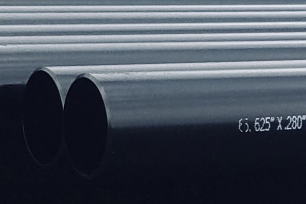 Close-up view of stacked black metal pipes with visible measurements marked on the side.