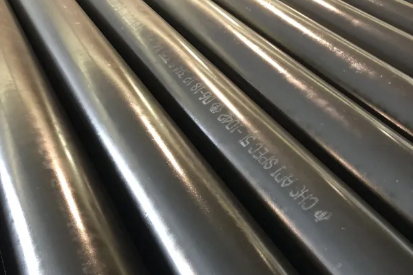 Close-up of black steel pipes with engraved text visible on the surface.